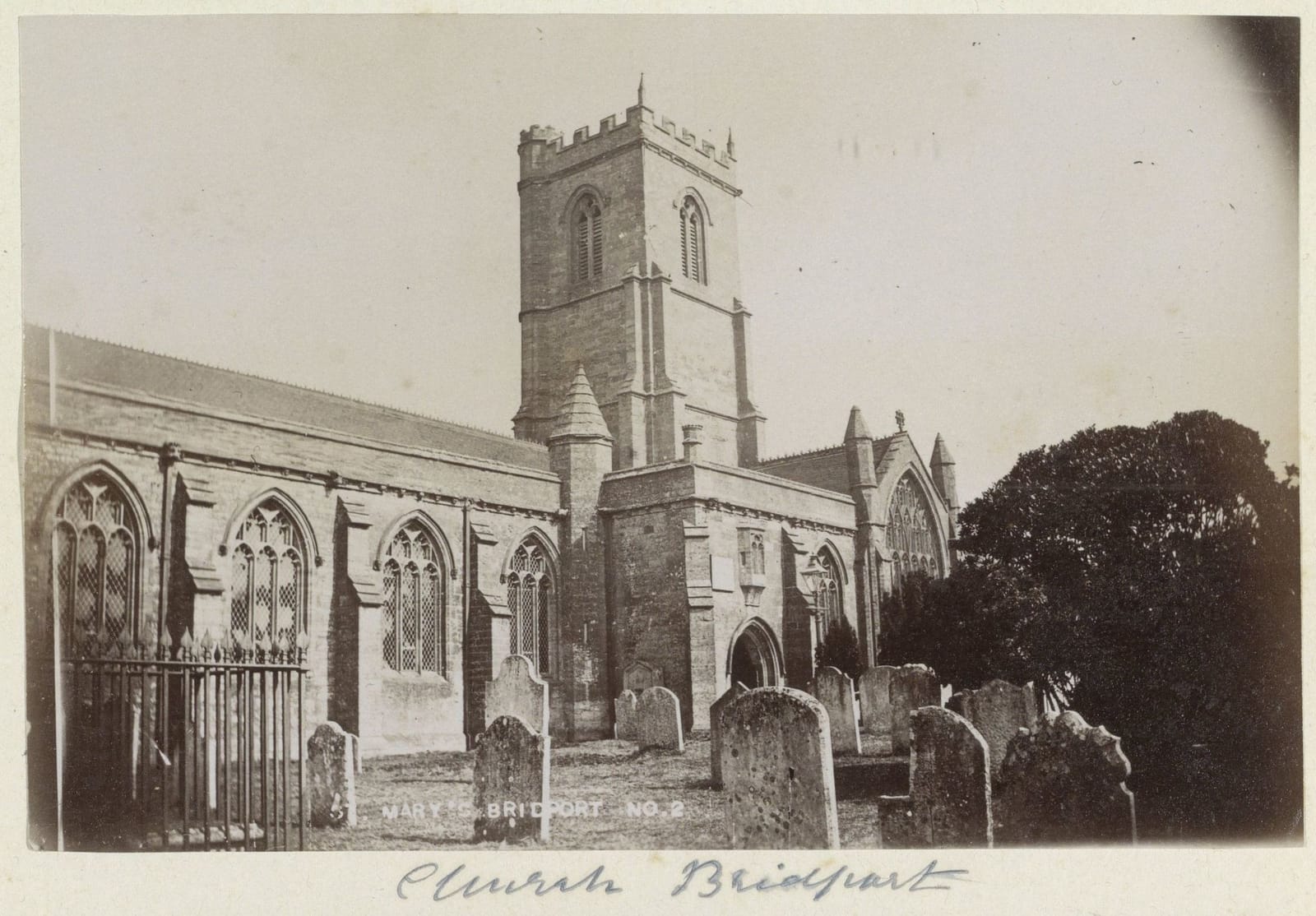 A photograph of a stone church with a square tower, gravestones in the churchyard in front.
