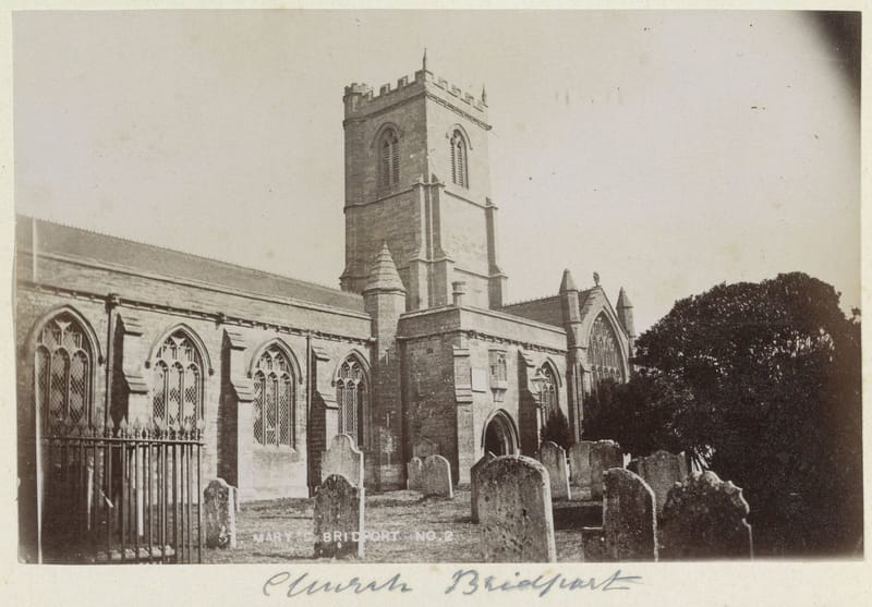 A photograph of a stone church with a square tower, gravestones in the churchyard in front.