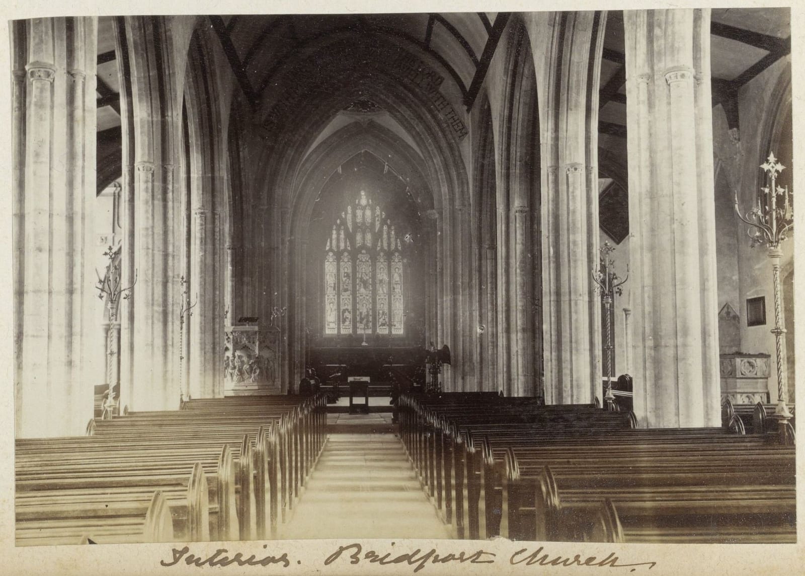 A photograph down the nave of a church between tall stone columns to the east window.