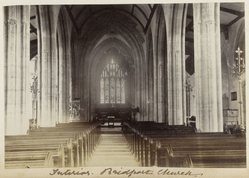 A photograph down the nave of a church between tall stone columns to the east window.