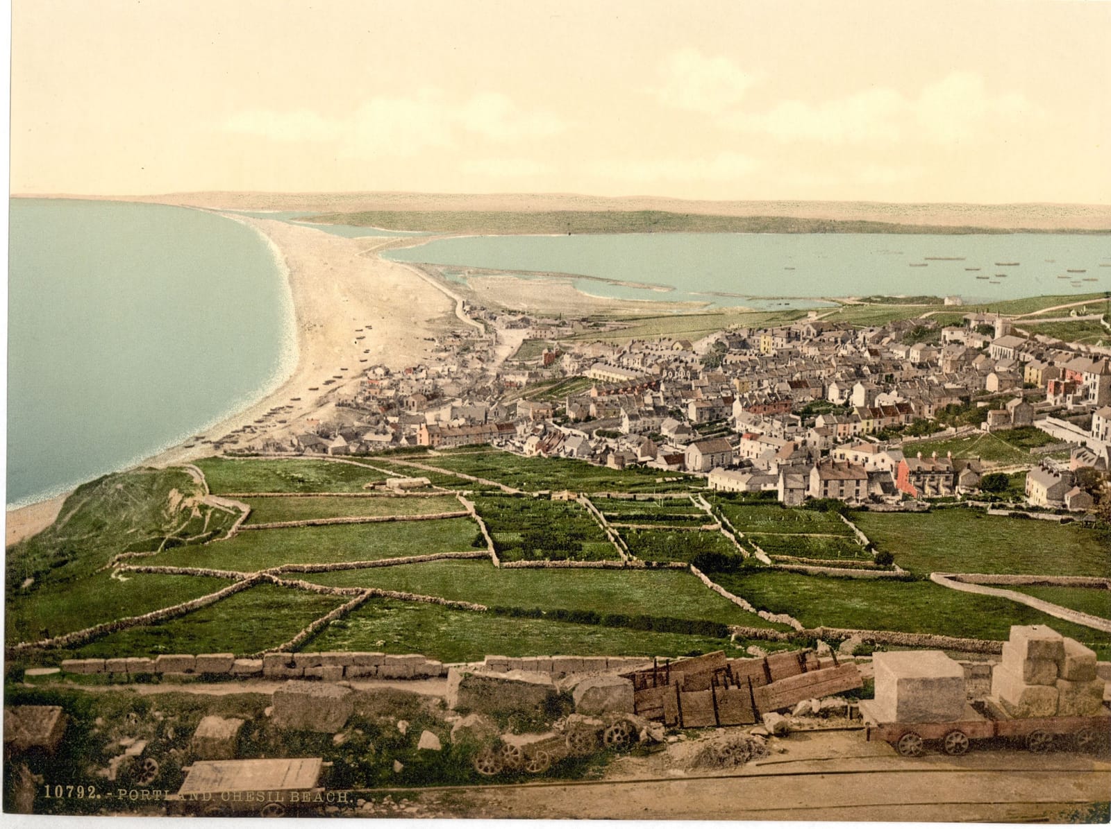 Looking down over a village of stone houses to the long straight bank of Chesil Beach running away along the coast.