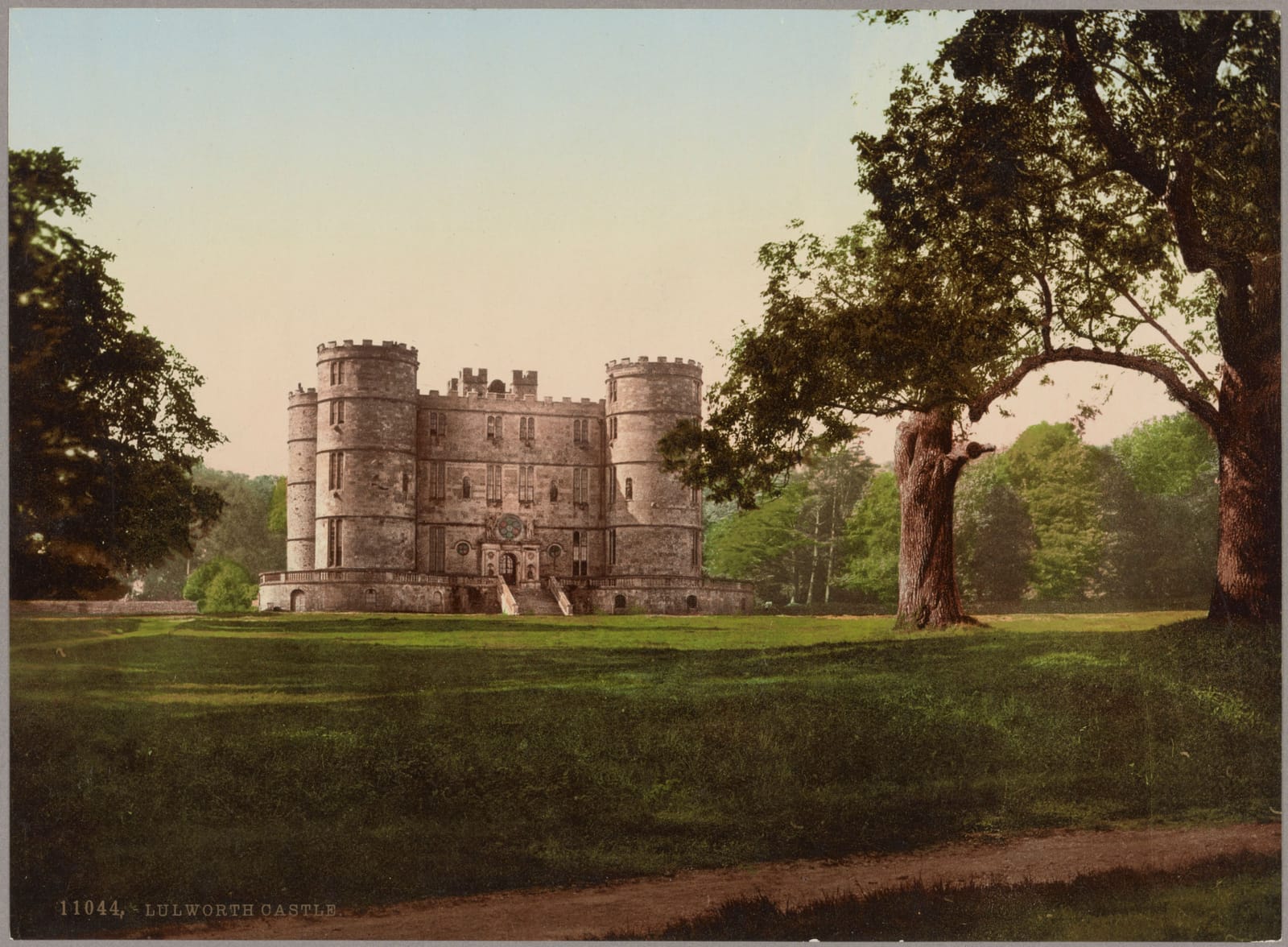 The square, turreted Lulworth Castle standing in open parkland under great trees.