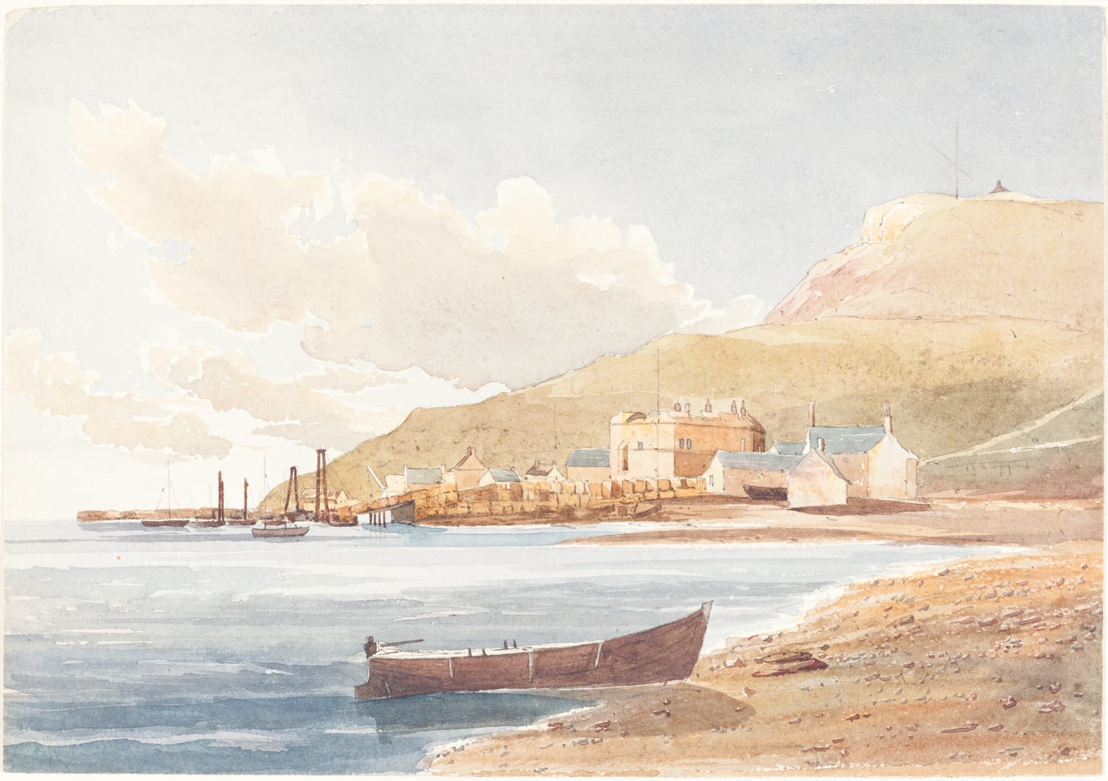 A low stone castle and houses on the shore below a green hill, with a red rowing boat on the beach and ships in the harbour.