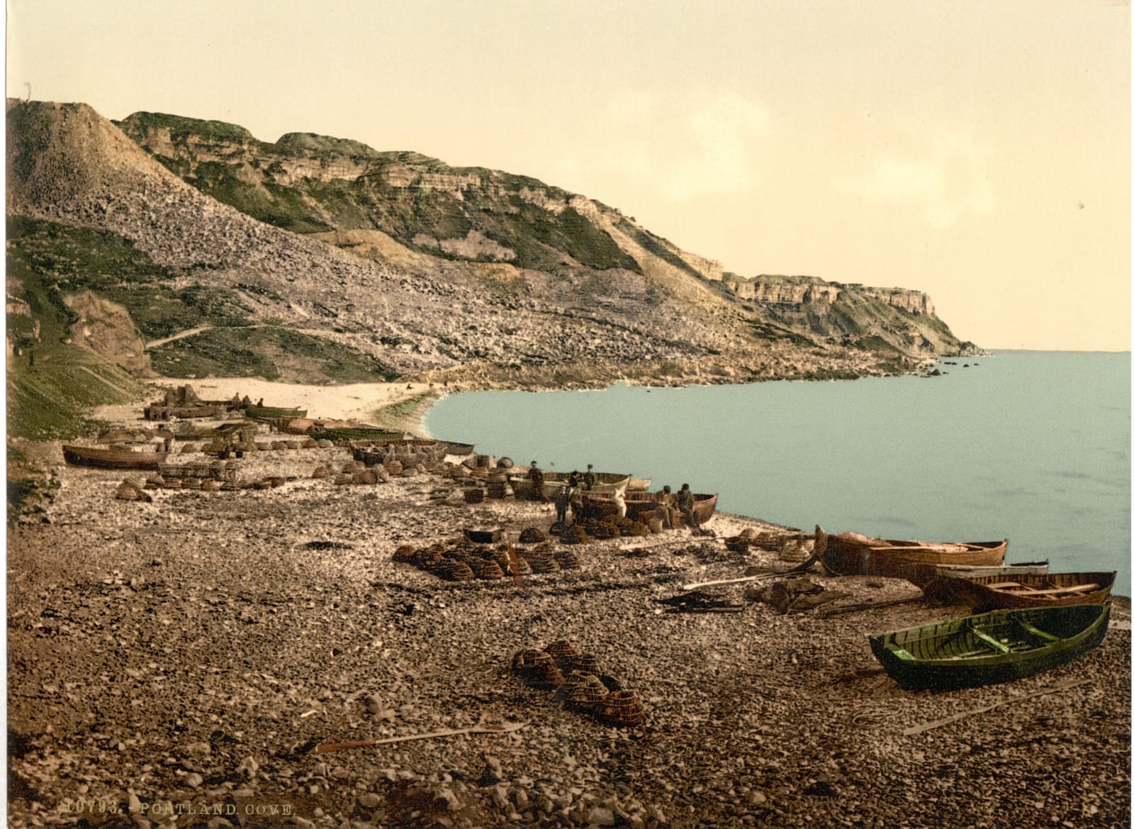 Fishing boats pulled up on a rocky beach beneath rough, broken cliffs.