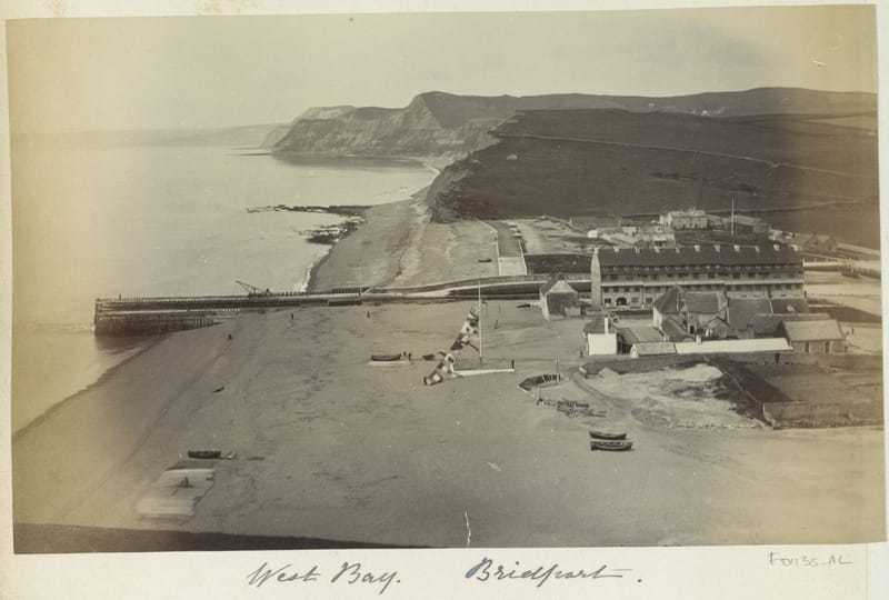 A photograph of the harbour and beach at West Bay, with the cliffs running away to the east.